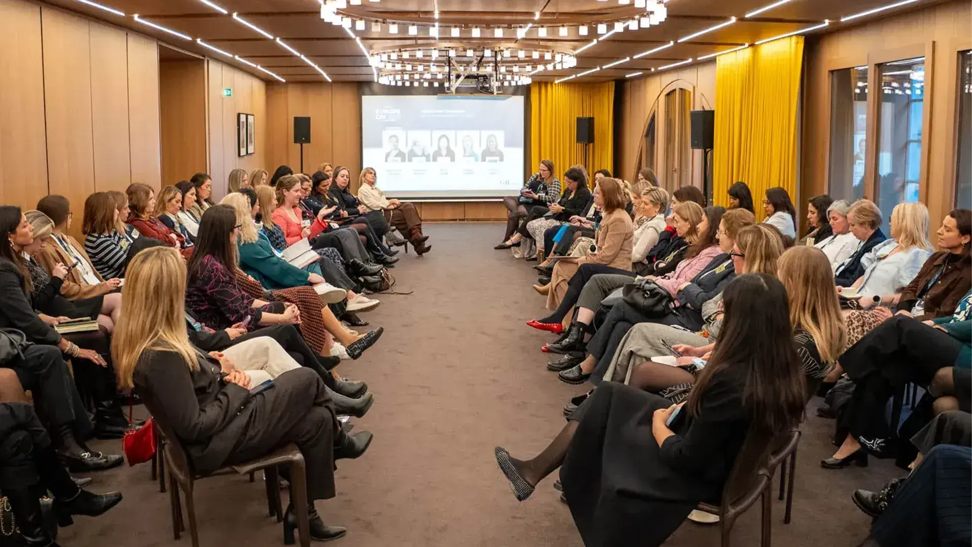 A large group of female real estate professionals gathered in a modern conference room for a GRI Institute forum.