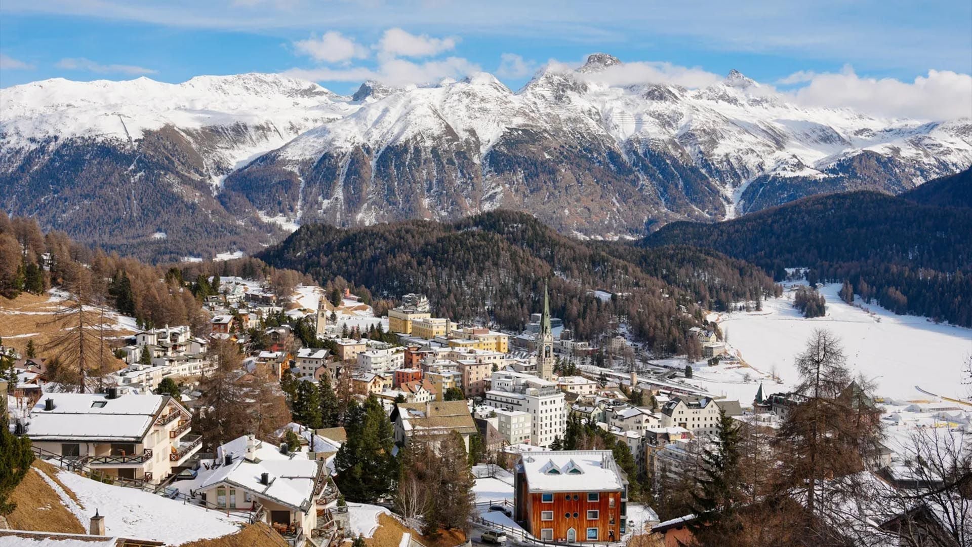 Scenic view over the Swiss town  of St Moritz showing mountains, snow, trees, and buildings
