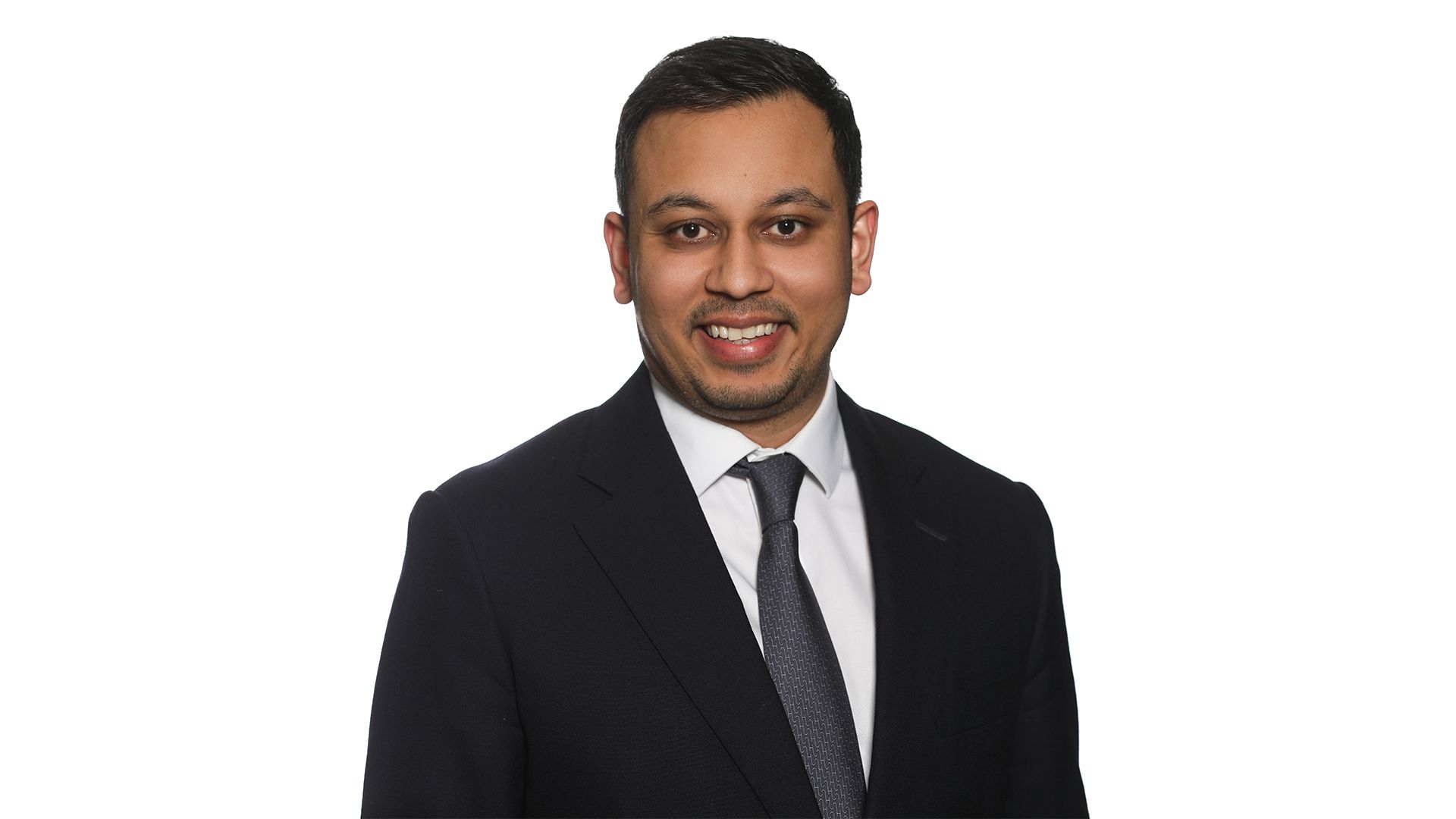 A professional headshot of Jai Patel from ICG, featuring a smiling man in a dark business suit, white dress shirt, and grey patterned tie, set against a plain white background.