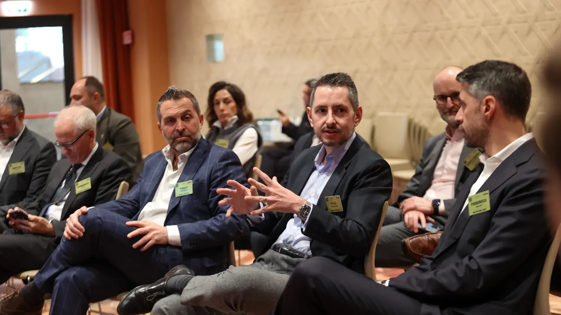 A close-up shot of three business professionals engaged in a discussion during a small group session at the GRI Hospitality Europe 2025 conference, focusing on real estate investment strategies.