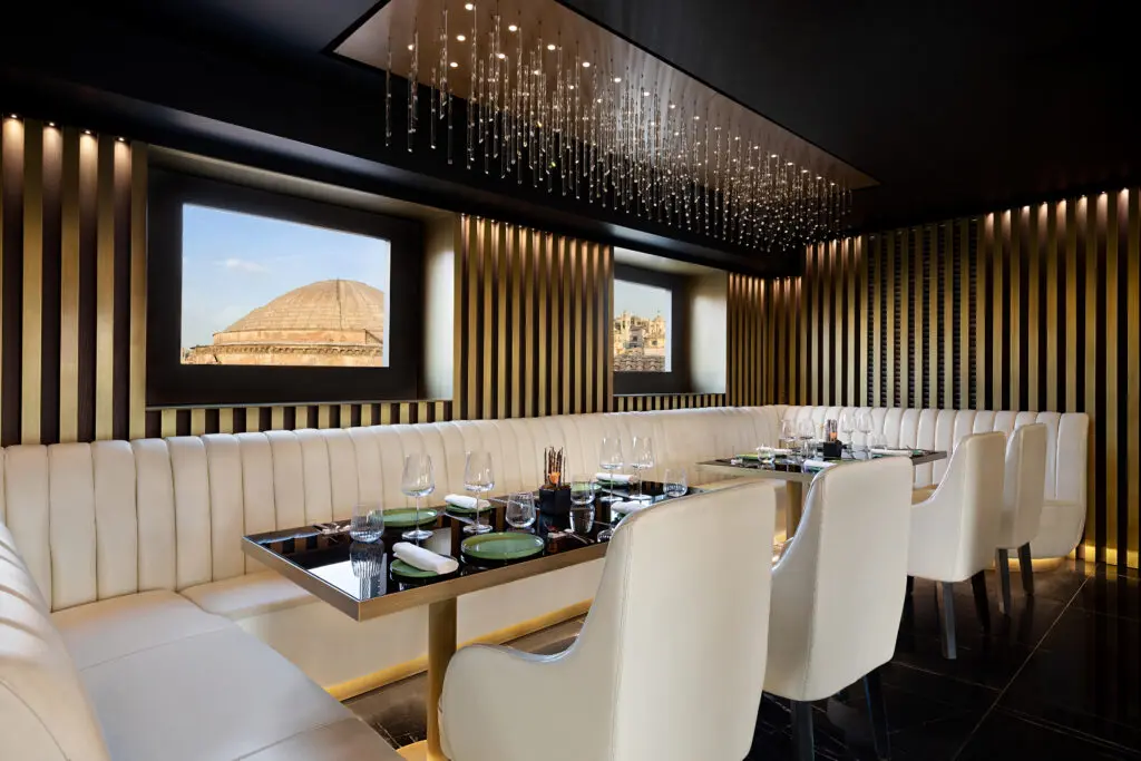 A detailed daytime view of the AK ROMPA hotel's restaurant, showcasing elegant table settings, unique light fixtures, and refined interior decor.