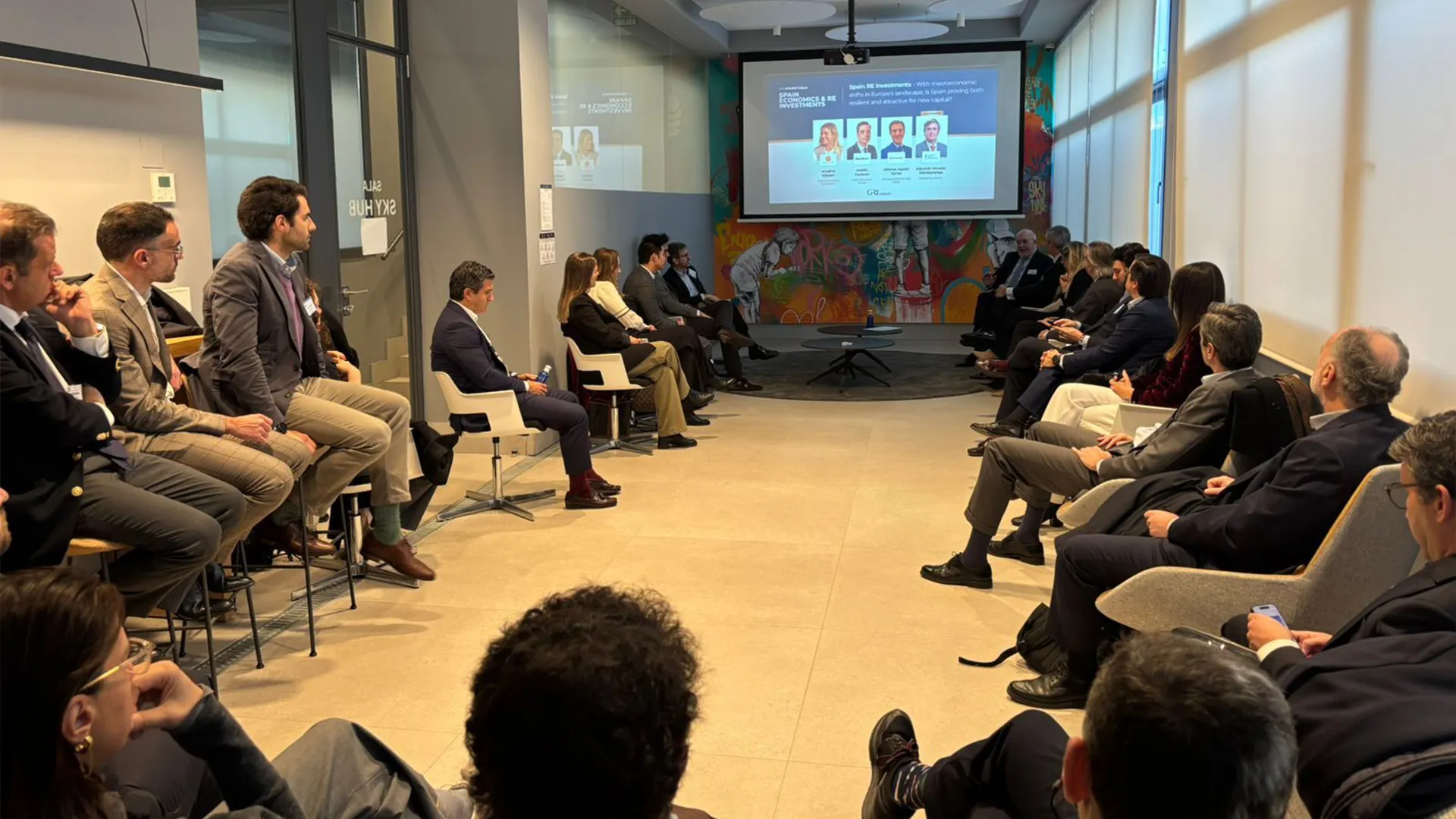 Industry leaders in a modern office space discussing Spanish economy and real estate