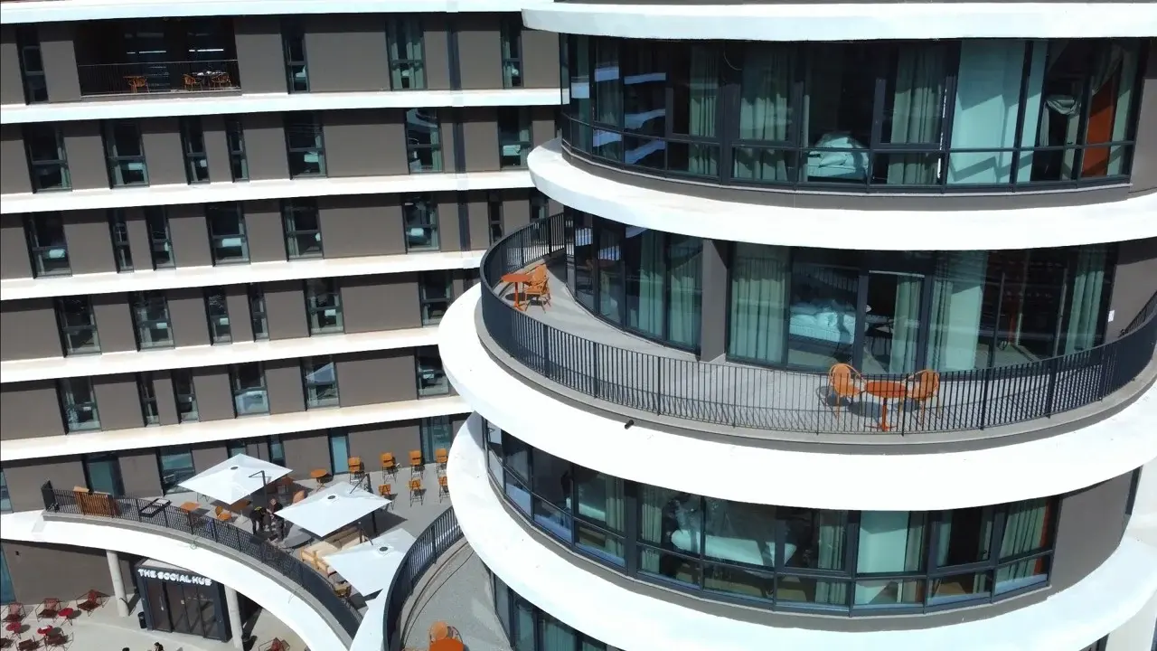 A serene, modern outdoor swimming pool, surrounded by unoccupied lounge chairs and contemporary architecture.