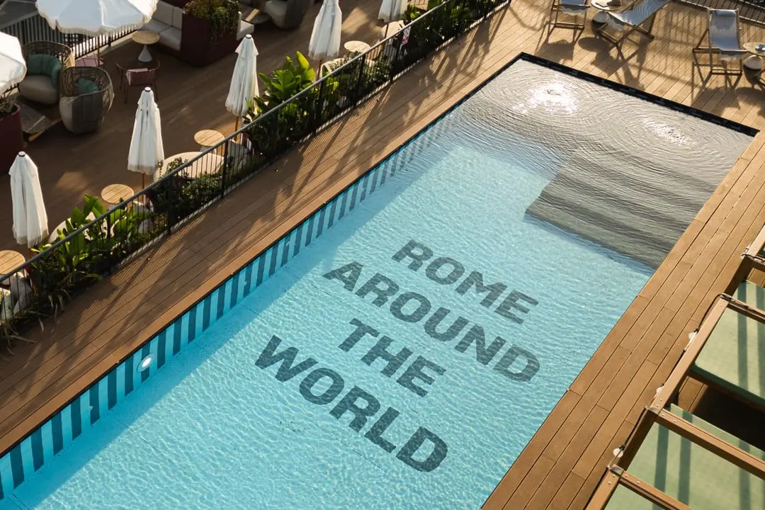 A serene, modern outdoor swimming pool, surrounded by unoccupied lounge chairs and contemporary architecture.