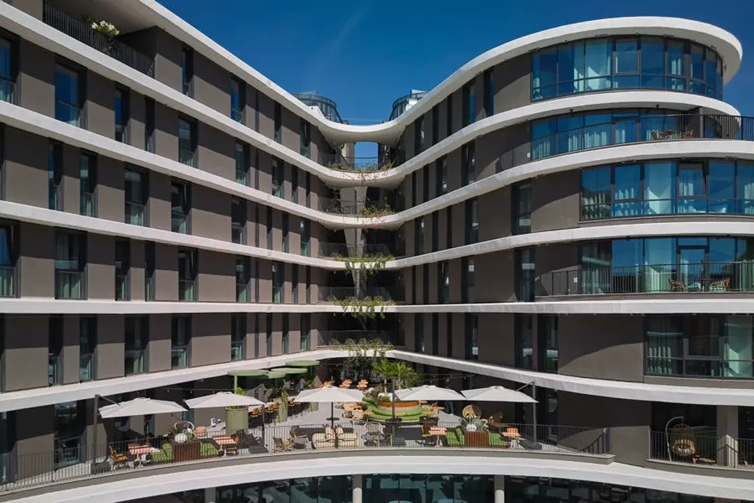 A vibrant rooftop terrace at The Social Hub in Rome, showcasing colorful seating areas, string lights, and panoramic city views under a clear sky.